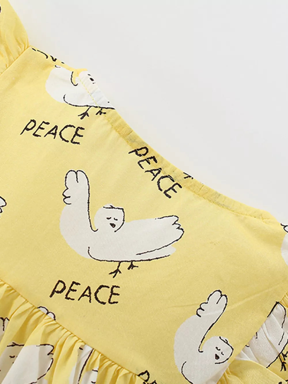Yellow cotton blend toddler dress with dove print and ruffle sleeves.