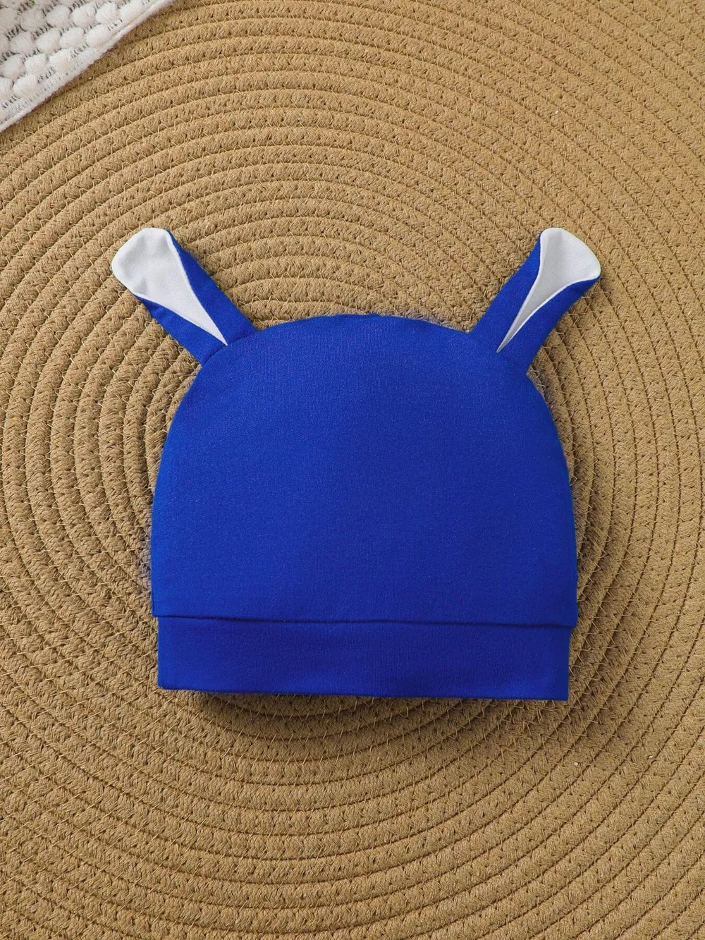 Blue baby hat with white bunny ears and fold-over brim.