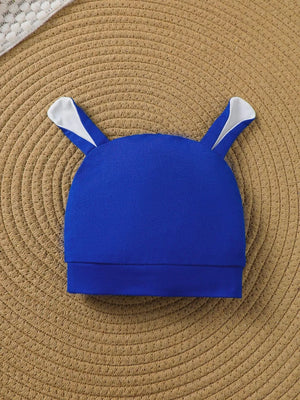 Blue baby hat with white bunny ears and fold-over brim.