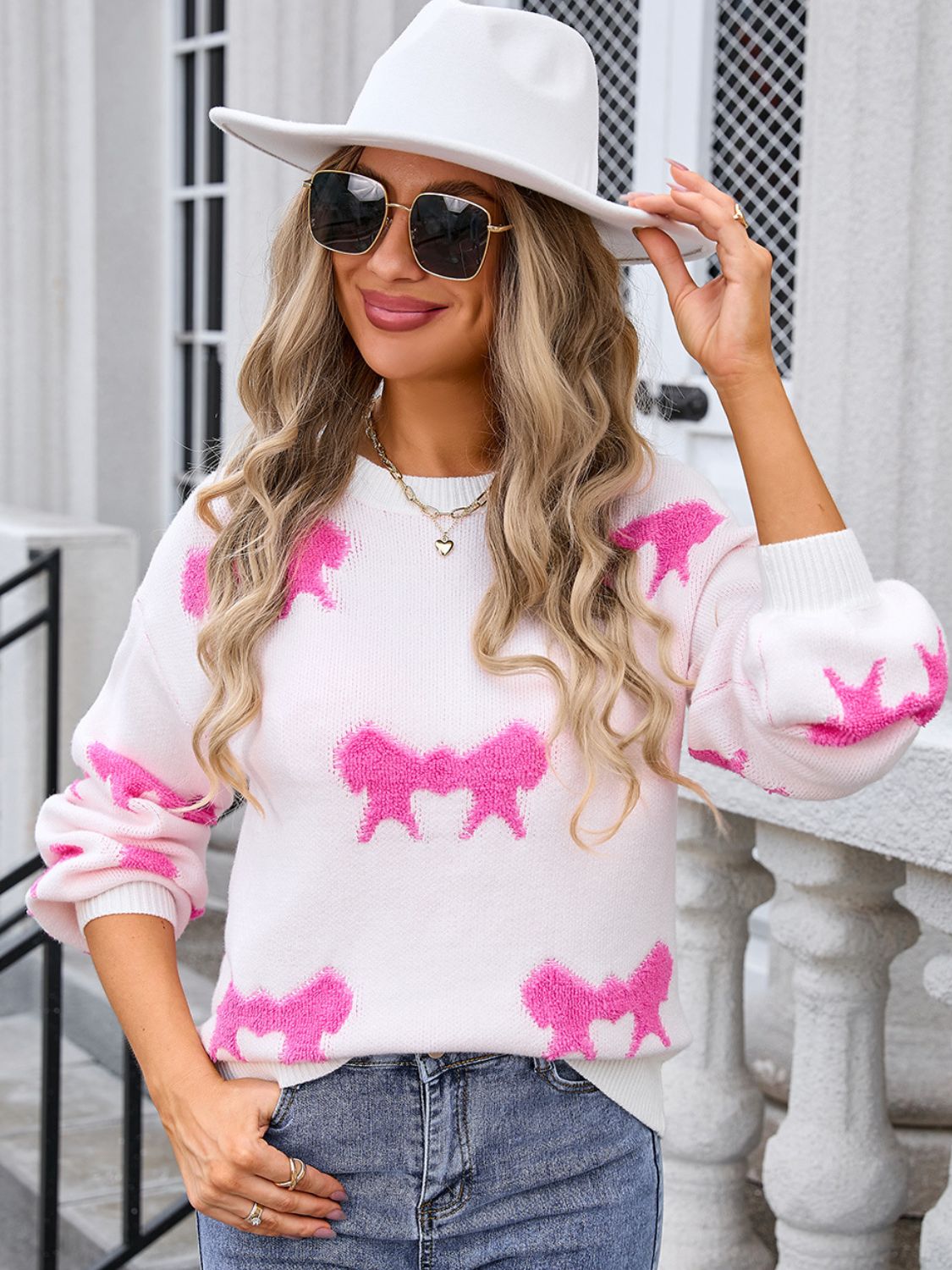 White knit pullover sweater with allover pink bow motif and crew neck.
