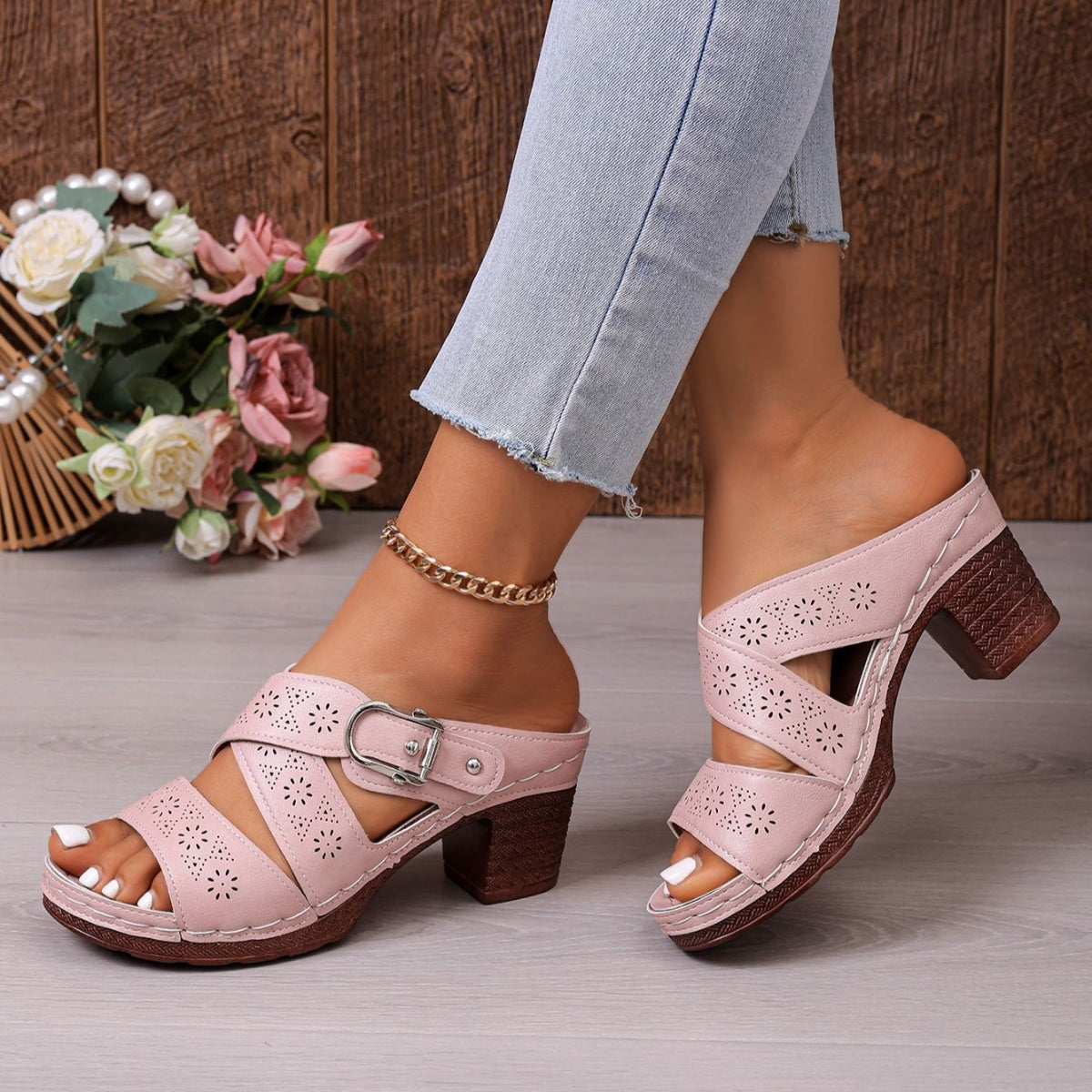 Pink laser-cut criss-cross block heel sandals with buckle detail and open toe.