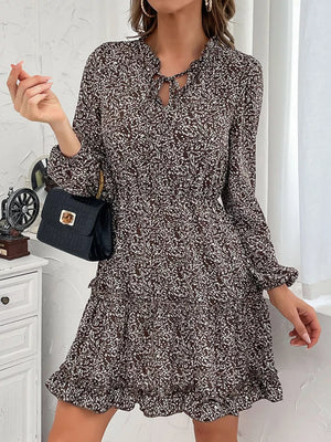 Ruffled tie neck floral mini dress in dark brown with long sleeves and tiered skirt.