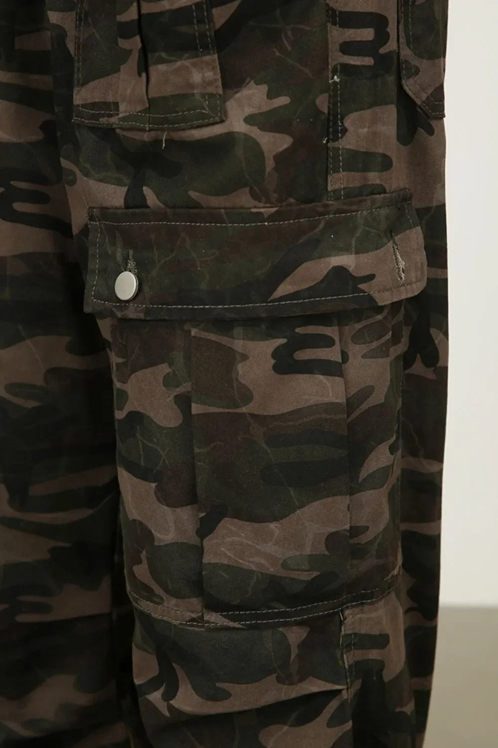 Wide-leg cargo trousers in green camouflage with multiple pockets and button closures.