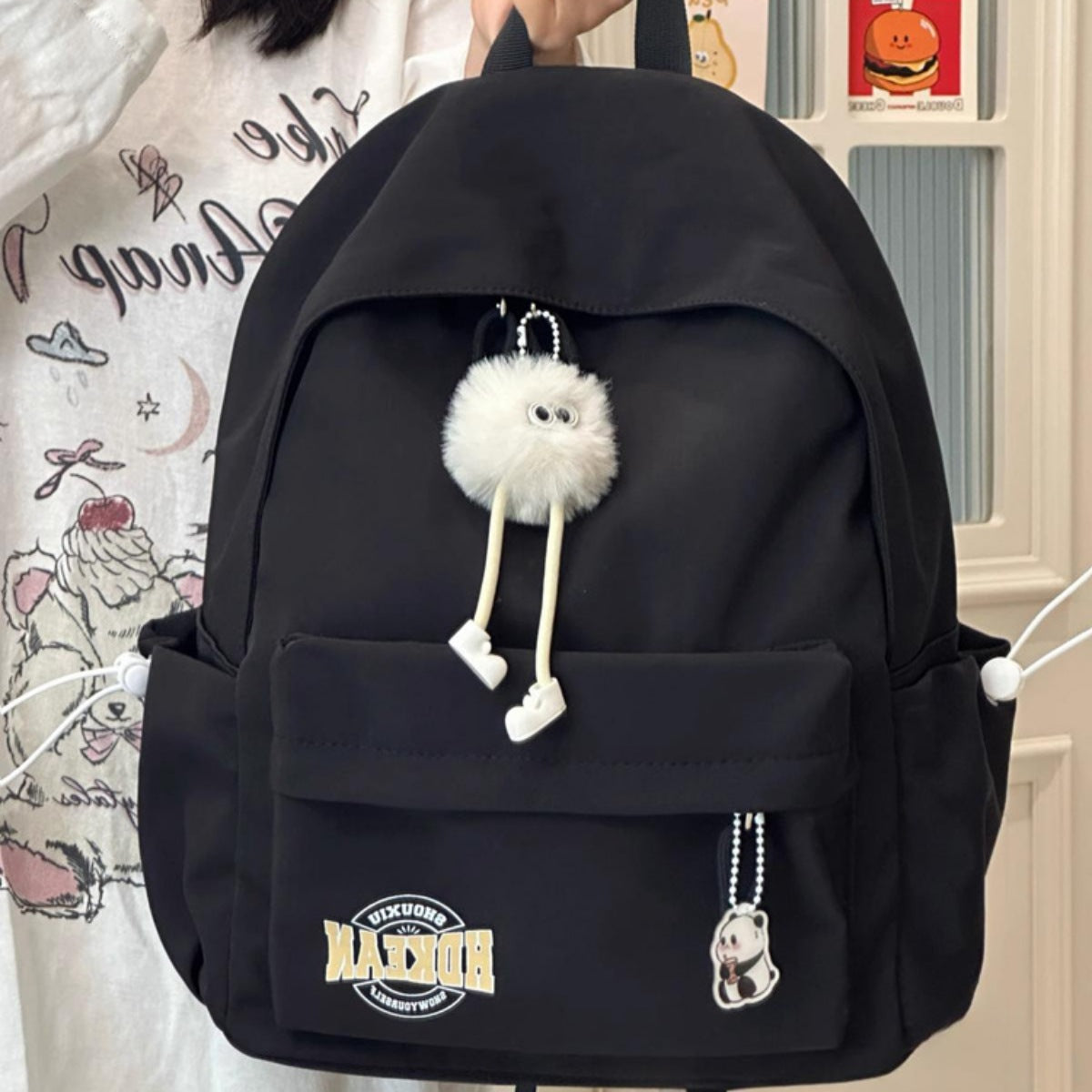 Black nylon backpack with fuzzy charm and panda keychain
