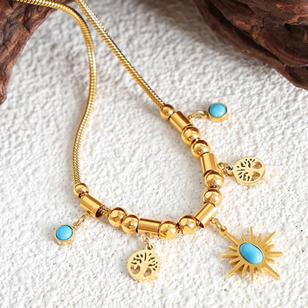 Gold celestial charm necklace with turquoise accents and tree charms