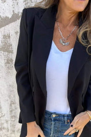 Black double-breasted blazer with sculpted lapels, worn open over a white tank top and jeans.