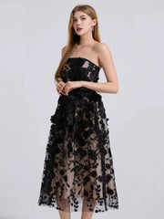Black strapless midi dress with intricate floral applique and sheer overlay.
