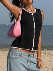 Black button-down sweater vest with white trim and pink buttons, sleeveless.