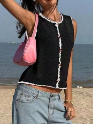 Black button-down sweater vest with white trim and pink buttons, sleeveless.