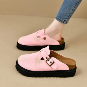 Pink embroidered denim platform clogs with buckle detail and cork sole.