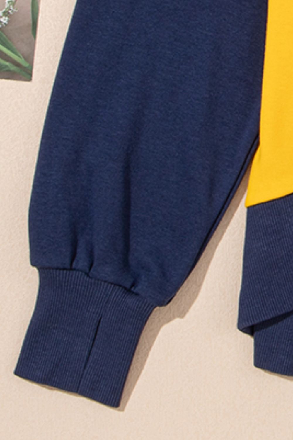Crewneck sweatshirt with navy blue sleeves and yellow colorblock detail.