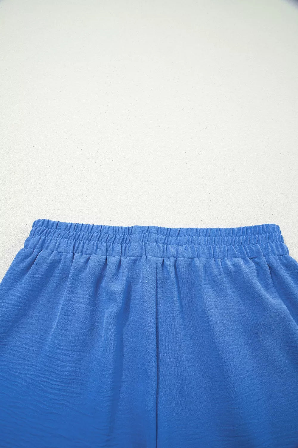 Blue drawstring shorts with elastic waistband and textured fabric detail.