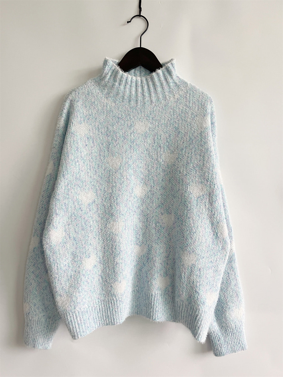 Mint blue acrylic turtleneck sweater with all-over white heart motif and textured knit.