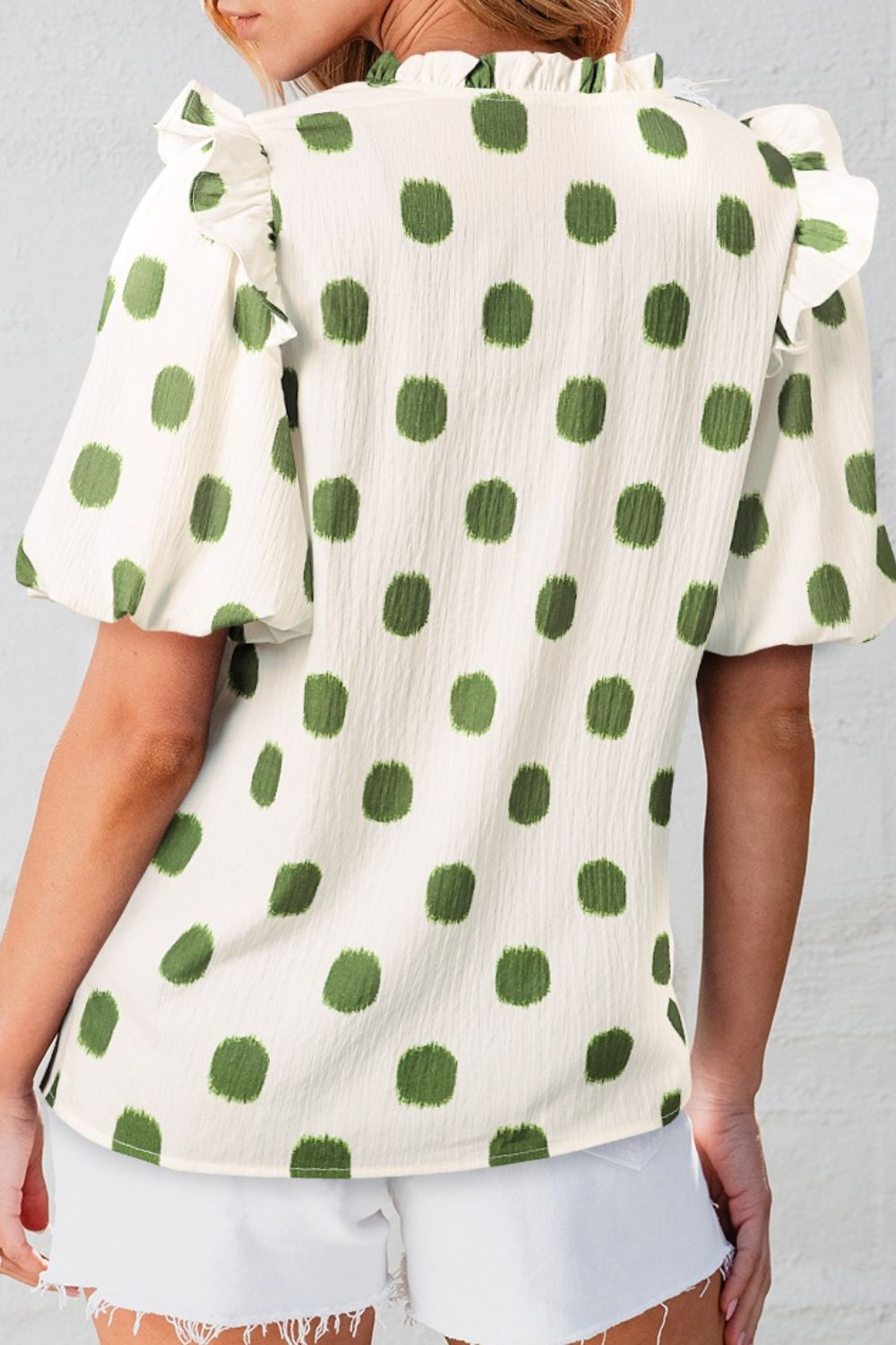 Textured polka dot blouse in matcha green with ruffled neckline and sleeves.