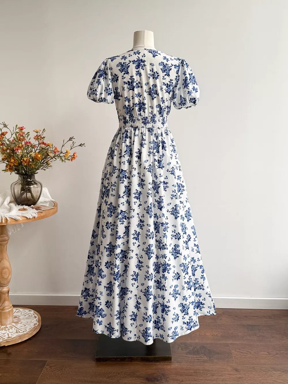 Maxi dress with white and blue floral print, V-neck, puff sleeves, and smocked waist.