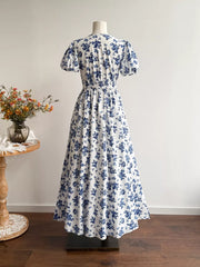 Maxi dress with white and blue floral print, V-neck, puff sleeves, and smocked waist.