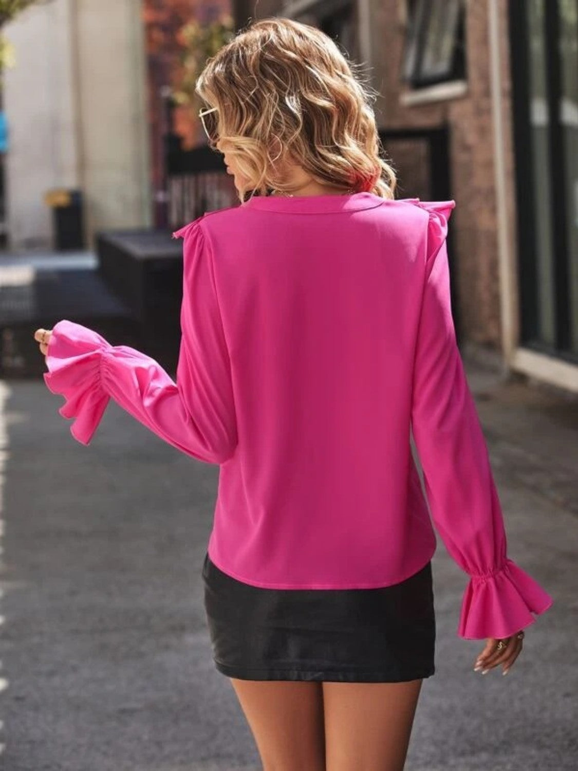 Pink polyester blouse with ruffled sleeves and neckline detail.