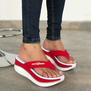 Red platform wedge sandals with elegant emblem detail and white sole.
