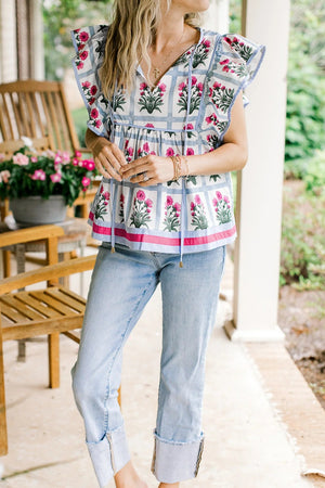 Women's ruffle sleeve blouse with floral print, tie neck, and blue plaid detail.