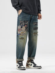 Men's distressed blue jeans with patchwork featuring teddy bears and paisley pattern.