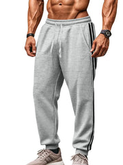 Gray joggers with black athletic stripes on the side, drawstring waist, and cuffed ankles.