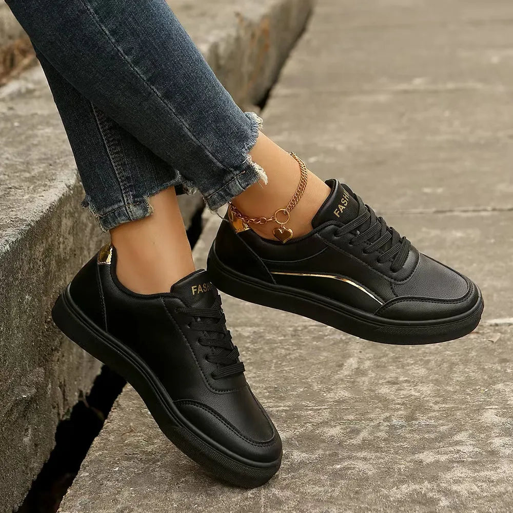 Black sneakers with gold metallic trim and laces.