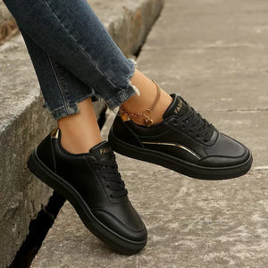 Black sneakers with gold metallic trim and laces.