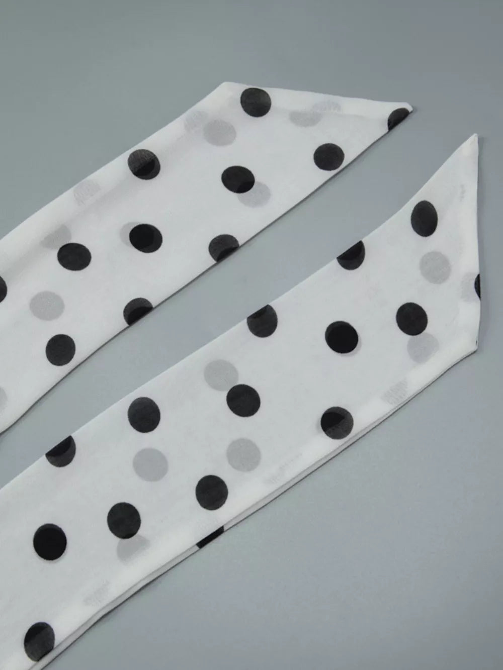 White polka dot scarf with black dots, a chic accessory.