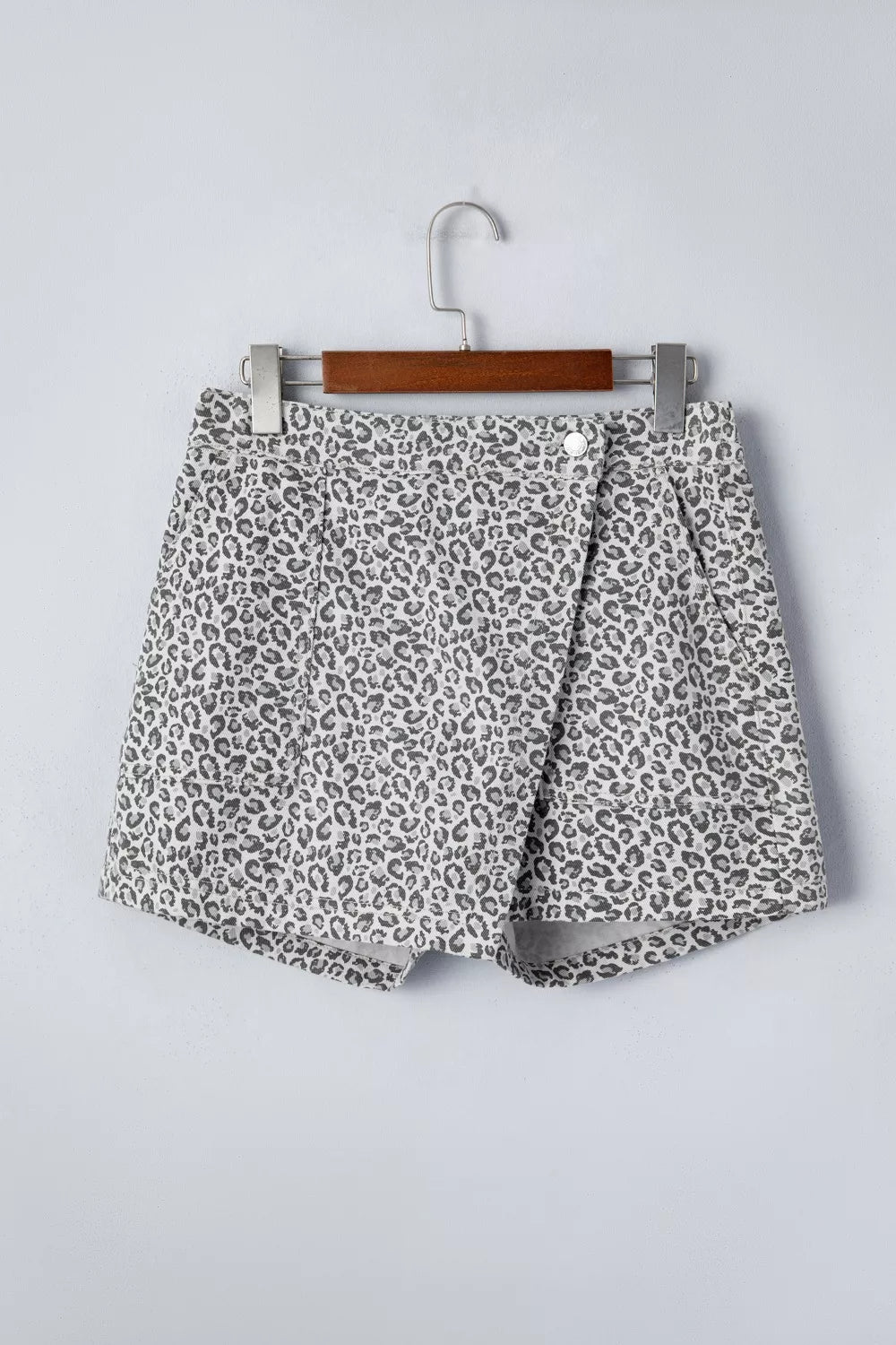 Denim shorts with leopard print, featuring a wrap-style front and button closure.