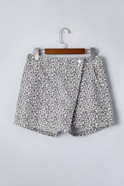 Denim shorts with leopard print, featuring a wrap-style front and button closure.