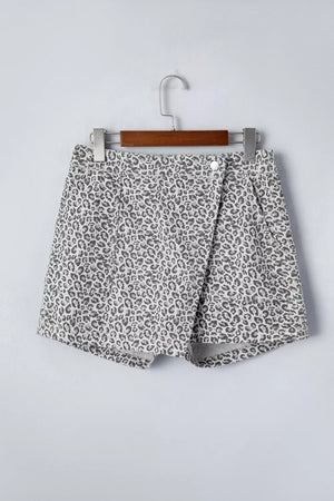 Denim shorts with leopard print, featuring a wrap-style front and button closure.