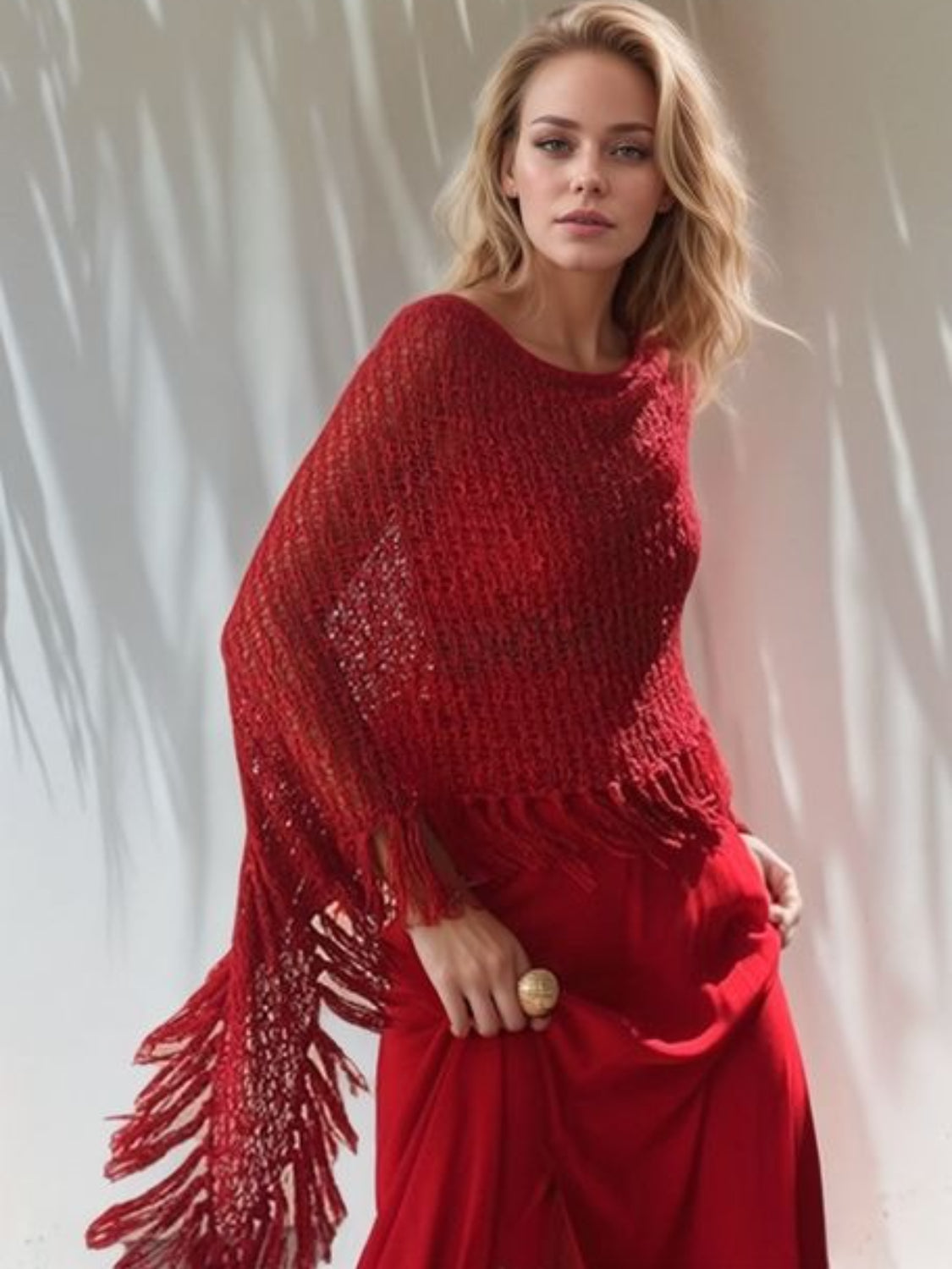 Open-knit red acrylic boat neck poncho with fringe trim detail.