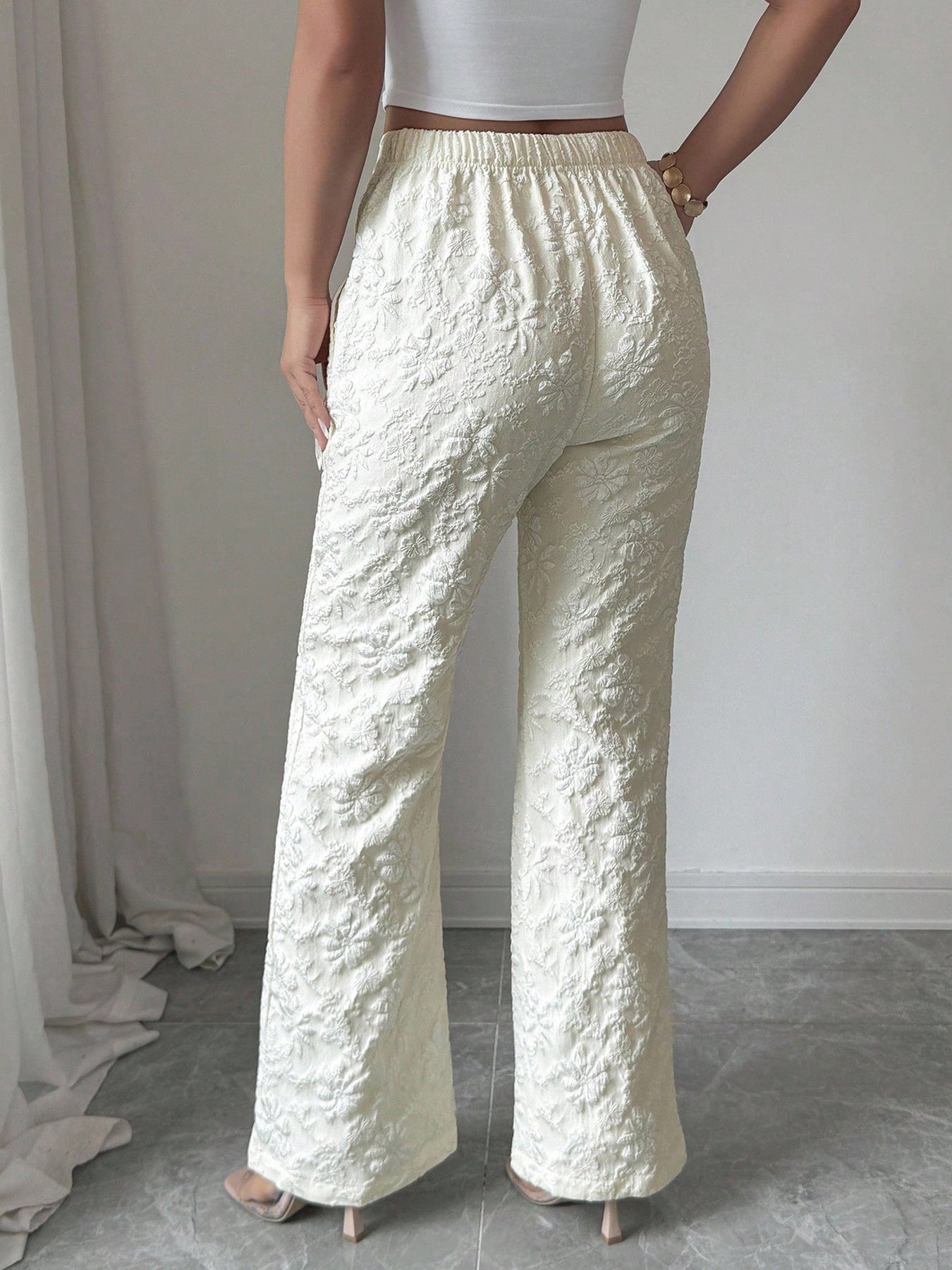 Textured cream high-waist wide-leg maternity pants with pockets and floral embroidery.