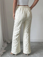 Textured cream high-waist wide-leg maternity pants with pockets and floral embroidery.