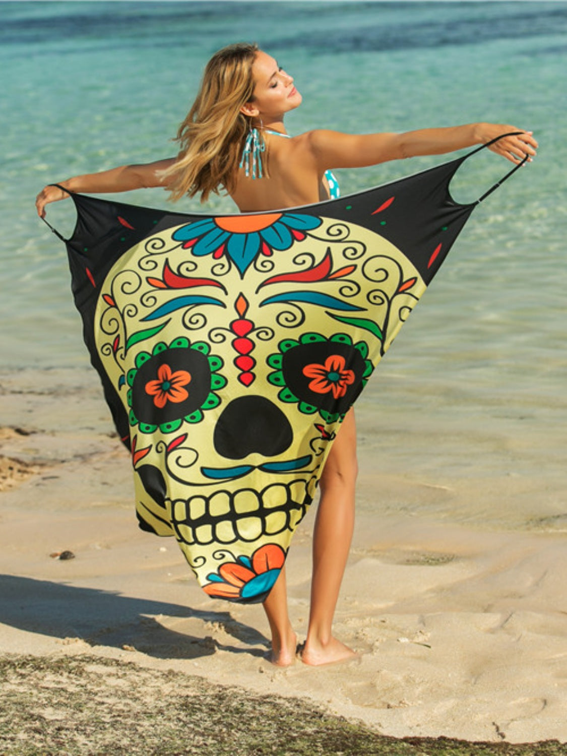 Yellow pareo wrap with a multicolor sugar skull graphic and black trim.
