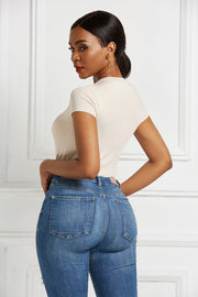 Ivory crew neck bodysuit with short sleeves, paired with blue denim jeans.