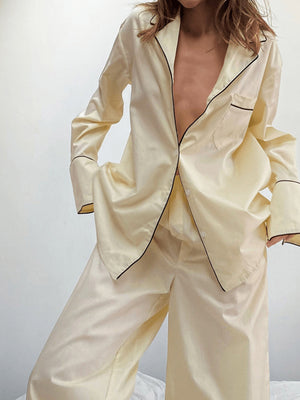 Cream button-up pajama set with black piping detail on collar, cuffs, and pocket.