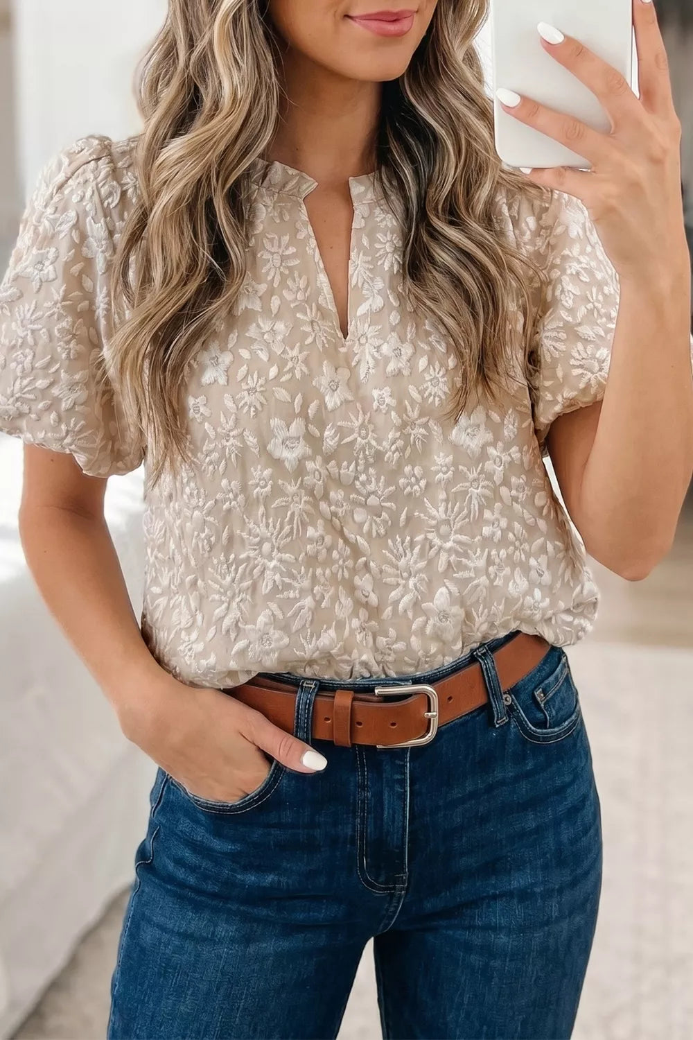 Charming floral jacquard shirt with puff sleeves and V-neck, styled with blue jeans.