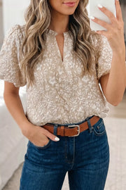 Charming floral jacquard shirt with puff sleeves and V-neck, styled with blue jeans.
