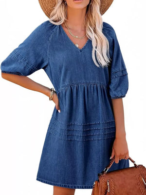 Denim mini dress with V-neck, puff sleeves, tiered skirt, and smocked waist in blue.