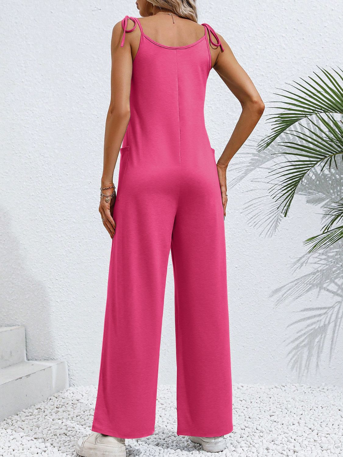Hot pink tie-strap wide leg jumpsuit with pockets and a relaxed fit.