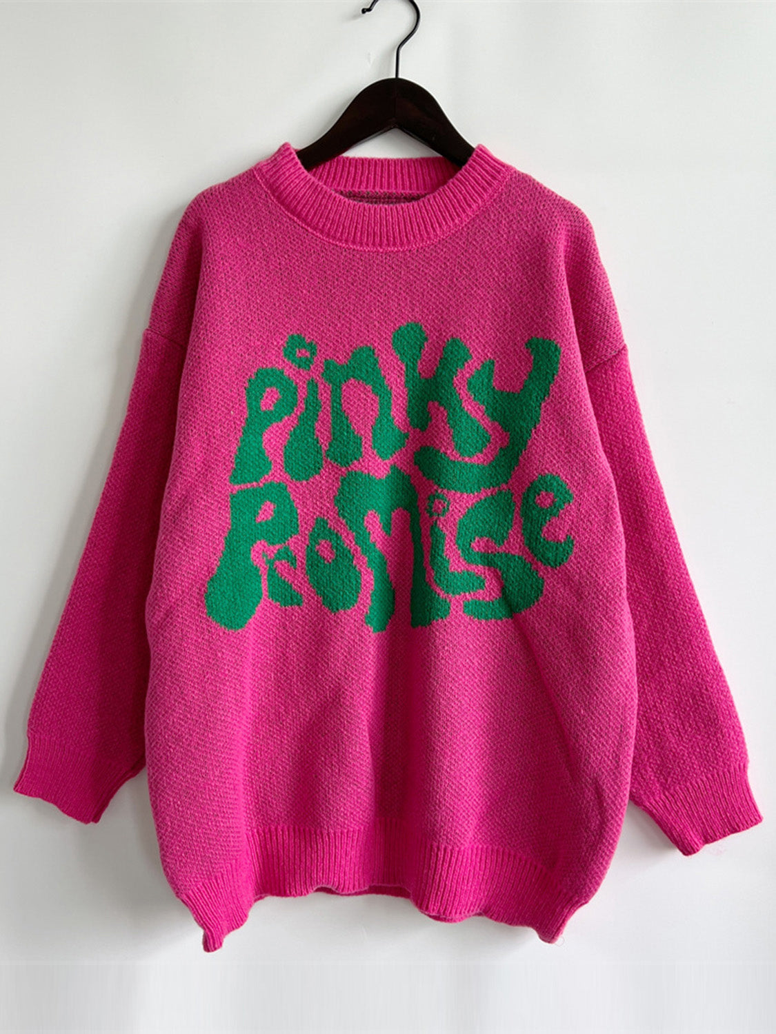 Pink knit jumper with green "Pinky Promise" graphic text, crew neck, long sleeves.