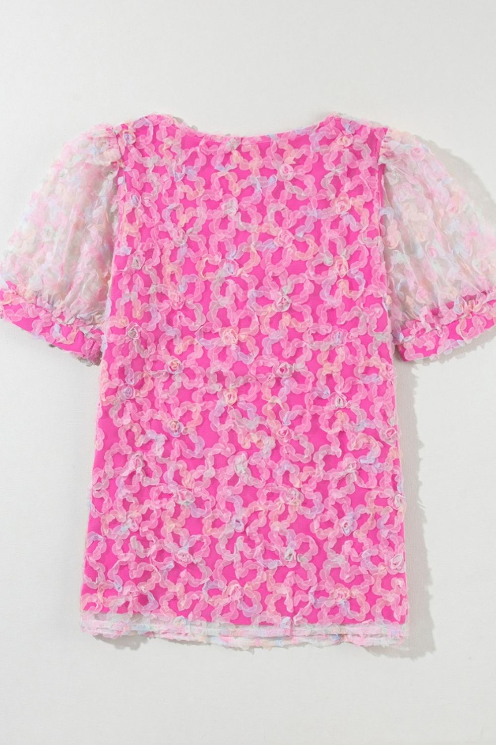 Fuchsia pink blouse with floral appliqué and sheer puff sleeves.