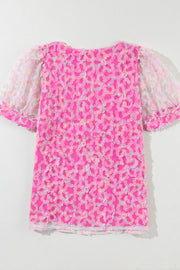 Fuchsia pink blouse with floral appliqué and sheer puff sleeves.