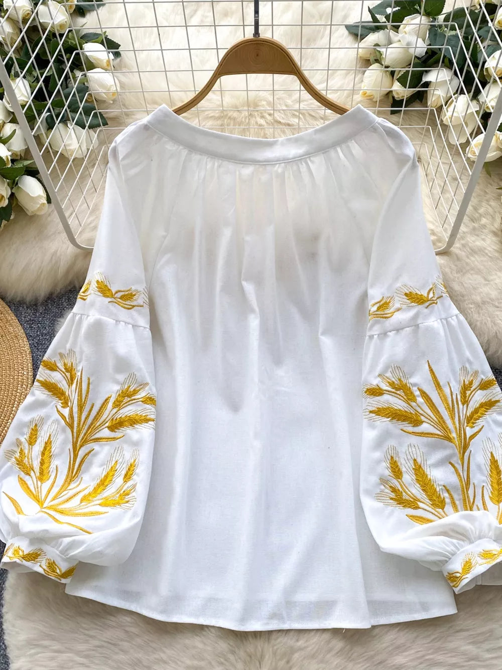 White embroidered tie-neck folk blouse with balloon sleeves and wheat detail.