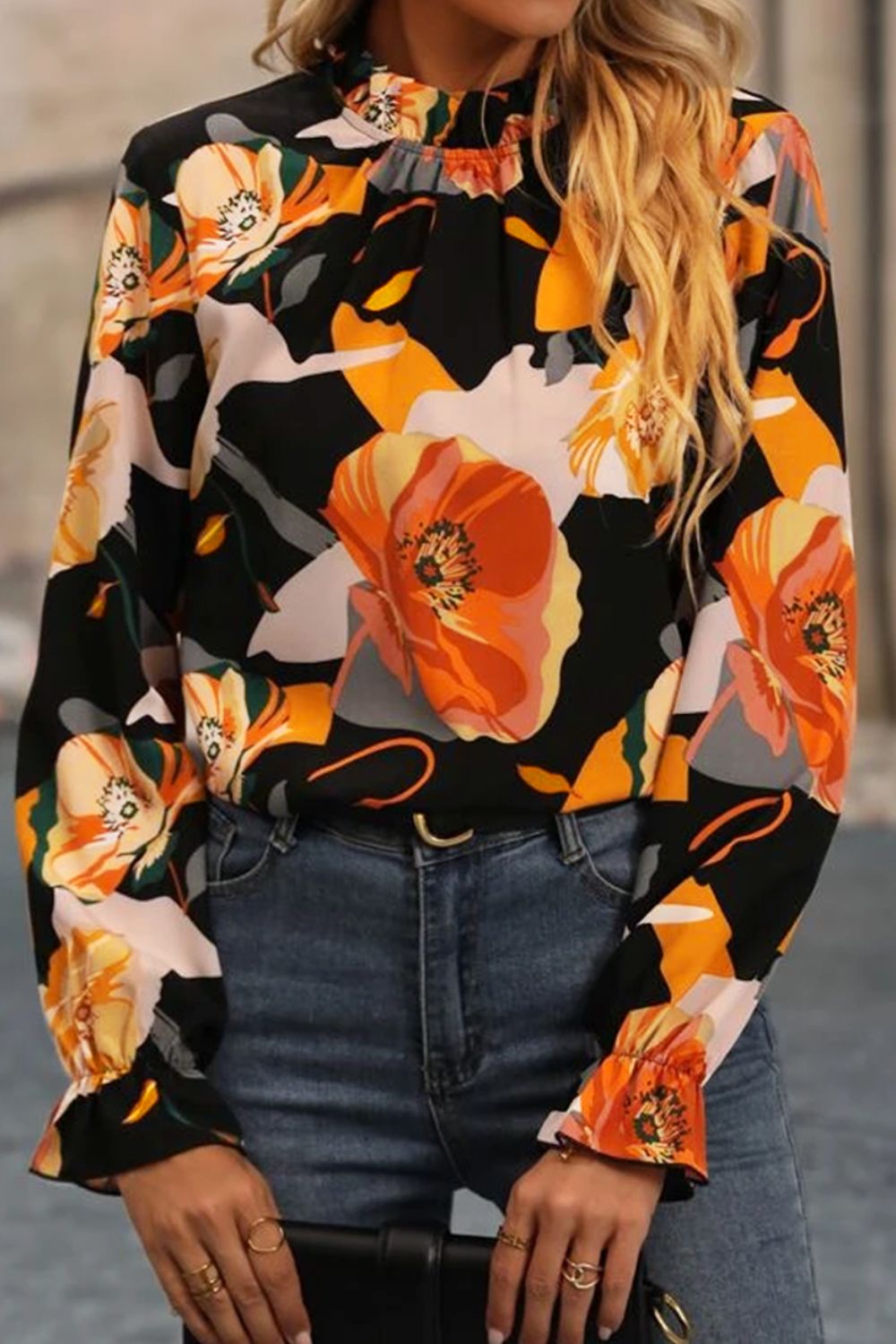 Black high-neck blouse with a bold floral print and ruffled cuffs.