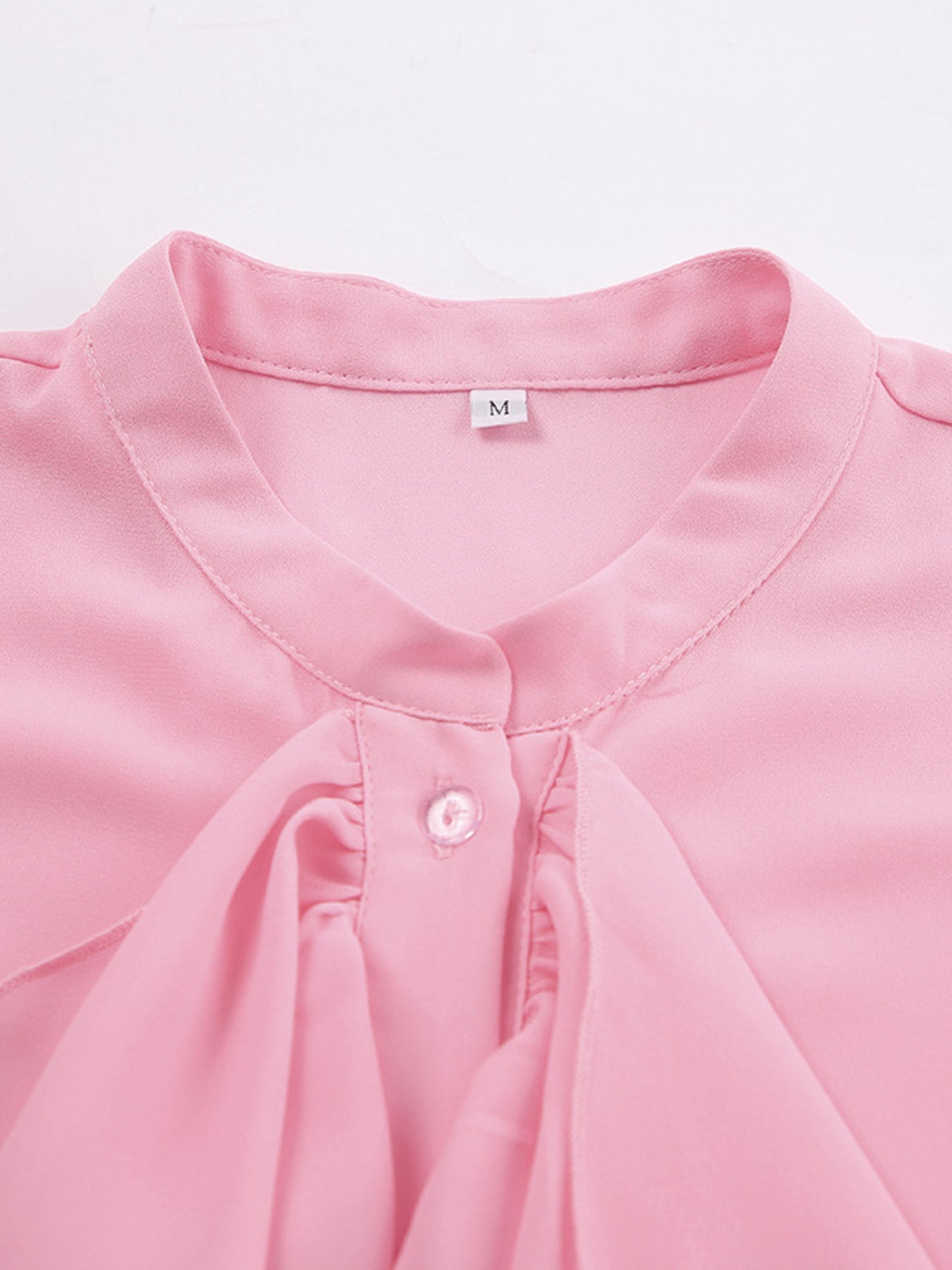 Pink ruffled flounce sleeve blouse with button detail and a tie neck.