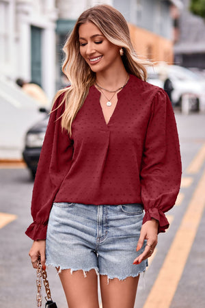 Burgundy textured dot V-neck blouse with ruffle cuffs and long sleeves.