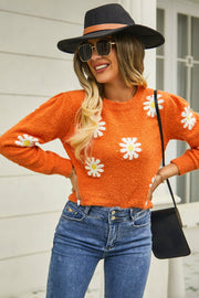 Orange textured knit sweater with white daisy motif, crew neck, and long sleeves.