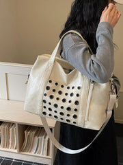 Cream travel organizer bag with eyelet detail and detachable strap.